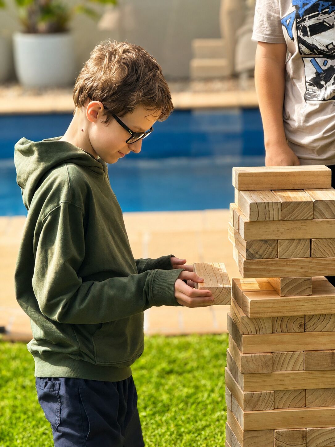 Friends playing giant Jenga by the pool